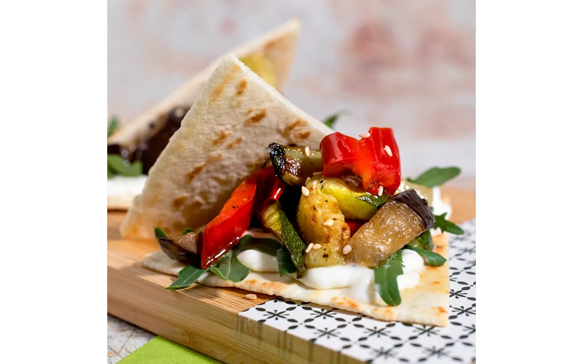 Piadina farcita con tris di verdure grigliate, cremoso squacquerone e rucola fresca, un classico romagnolo.