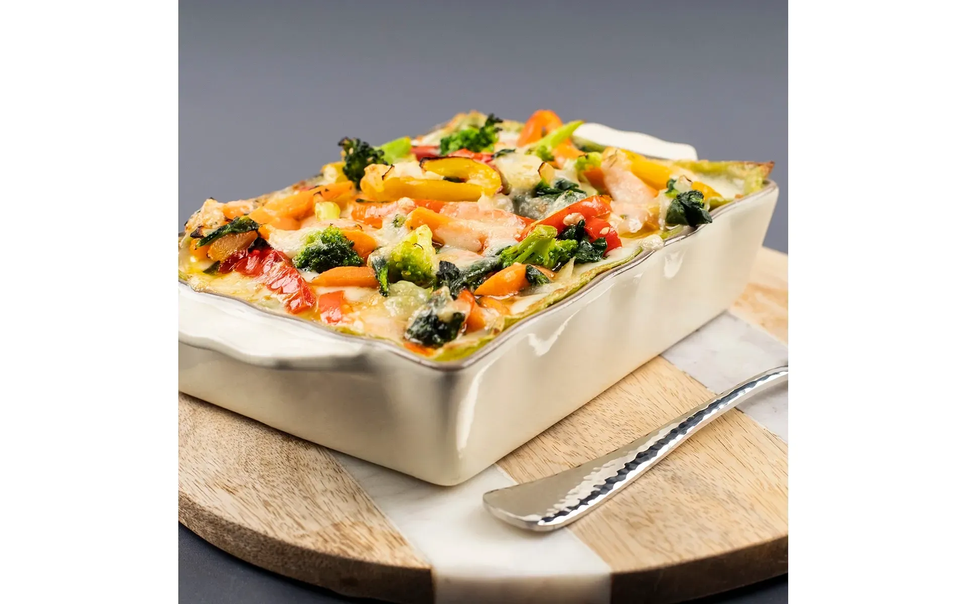 Porzione di lasagna verde Orogel, con strati di pasta fresca, ragù saporito e besciamella cremosa, in piatto bianco.