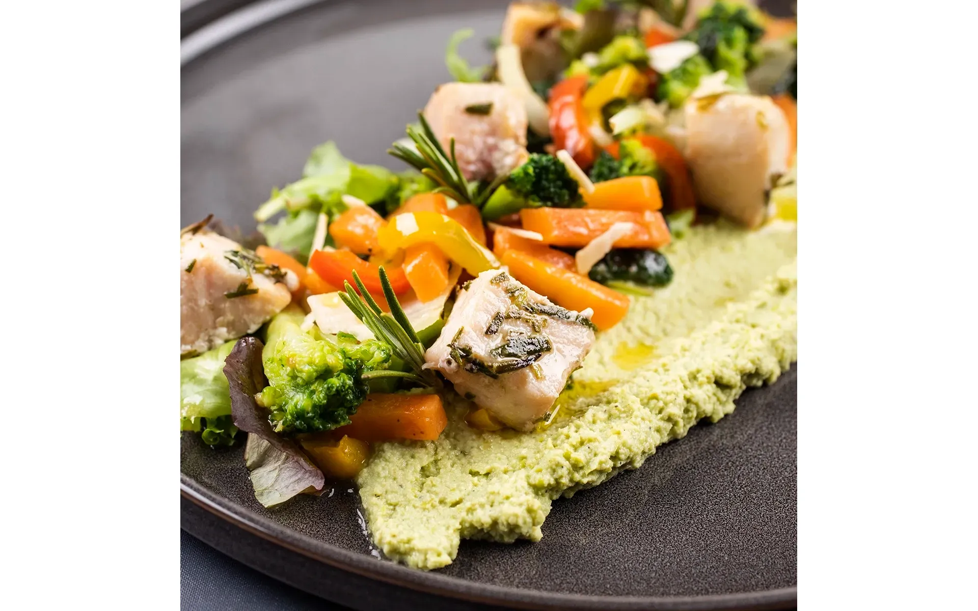 Piatto con cubetti di pollo o altra carne, serviti con un contorno di verdure fresche e saporite.