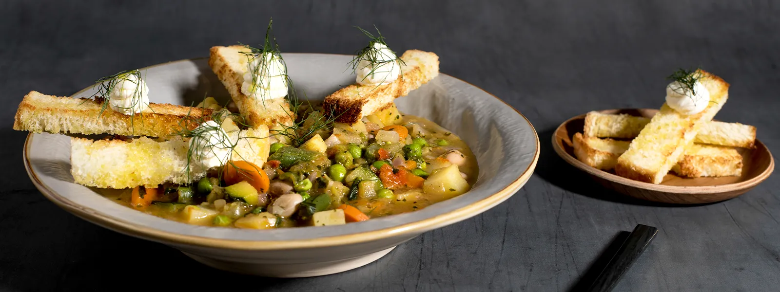 Ciotola di zuppa calda , accompagnata da pane croccante e verdure fresche, un comfort food.