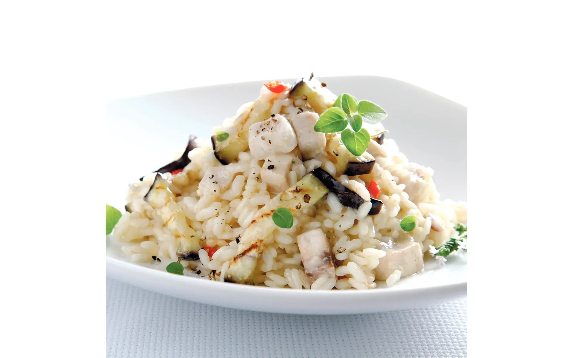 Risotto Orogel alla mantecatura perfetta: un piatto bianco con riso cremoso e verdure fresche.