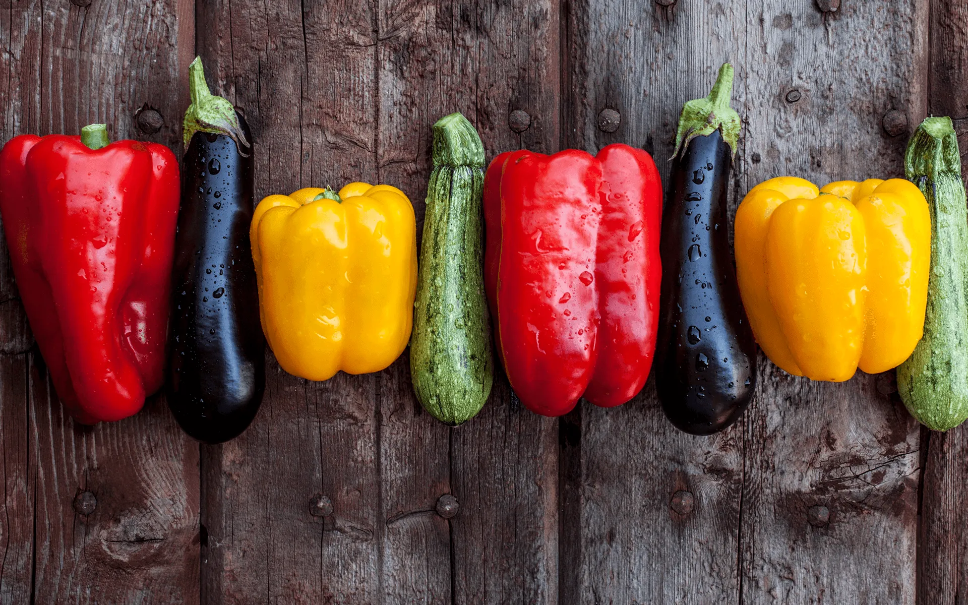 Peperoni, zucchine e melanzane Orogel fresche adagiate su un tavolo di legno