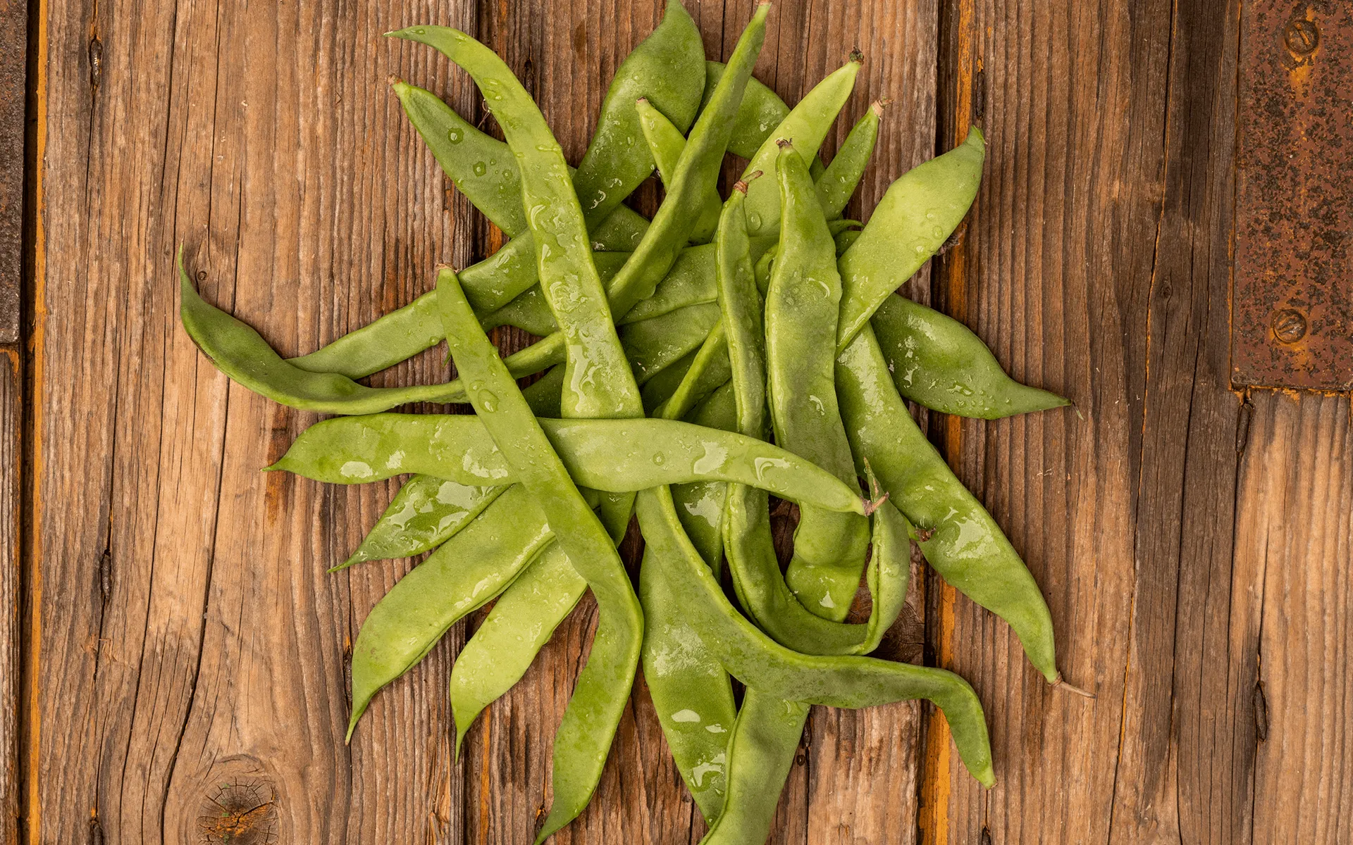 Contorno Amico Orogel, un mix di cinque verdure selezionate, con piselli freschi su un tavolo di legno.