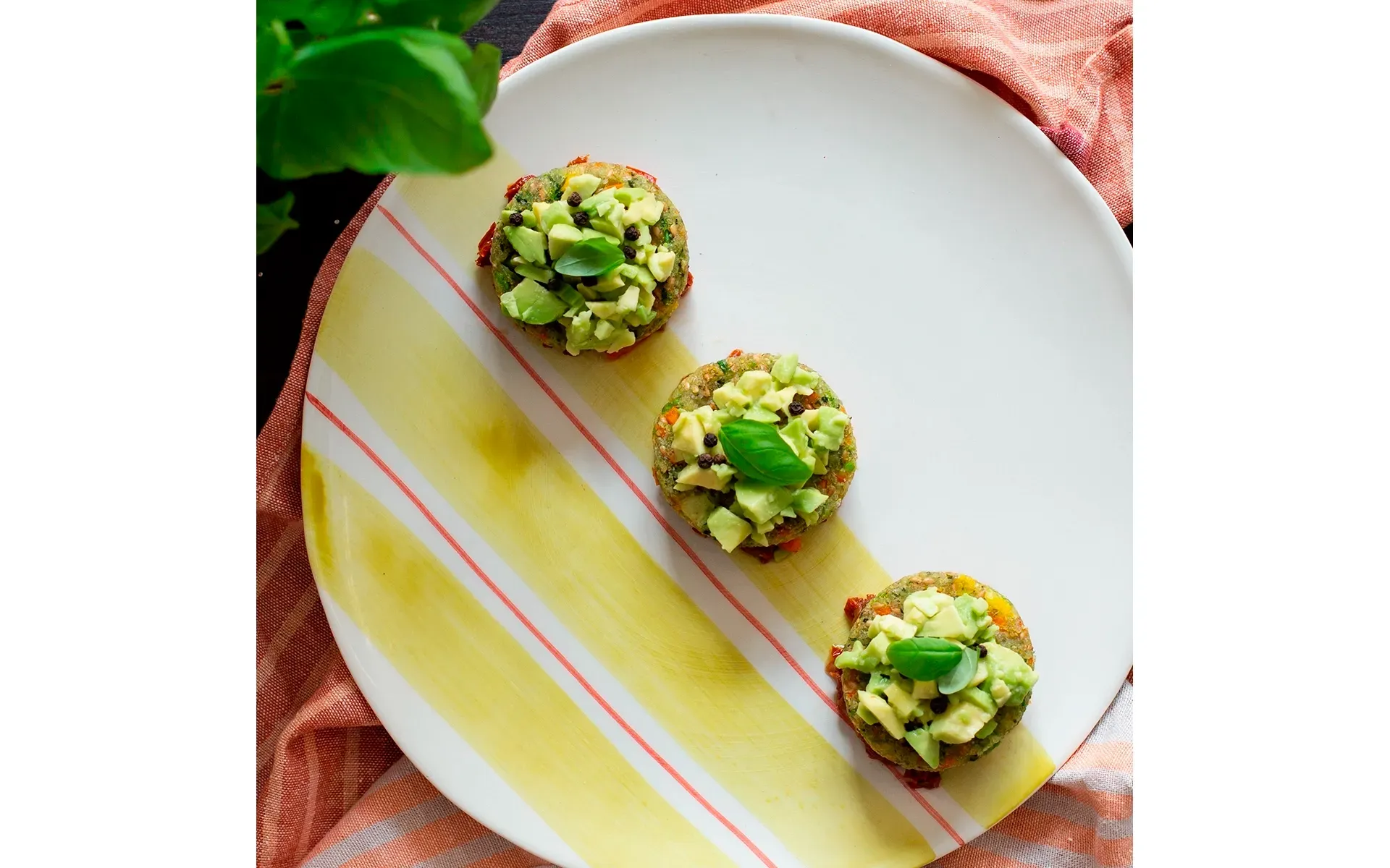 Mini burger Orogel, magari vegetali, serviti con fette di avocado fresco per un tocco esotico.