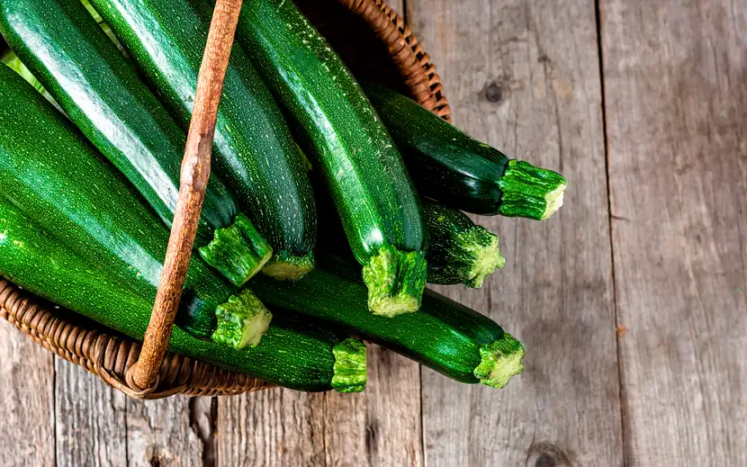 Zucchine fresche verdi disposte su un tavolo di legno, ortaggi leggeri e ricchi di proprietà nutrizionali