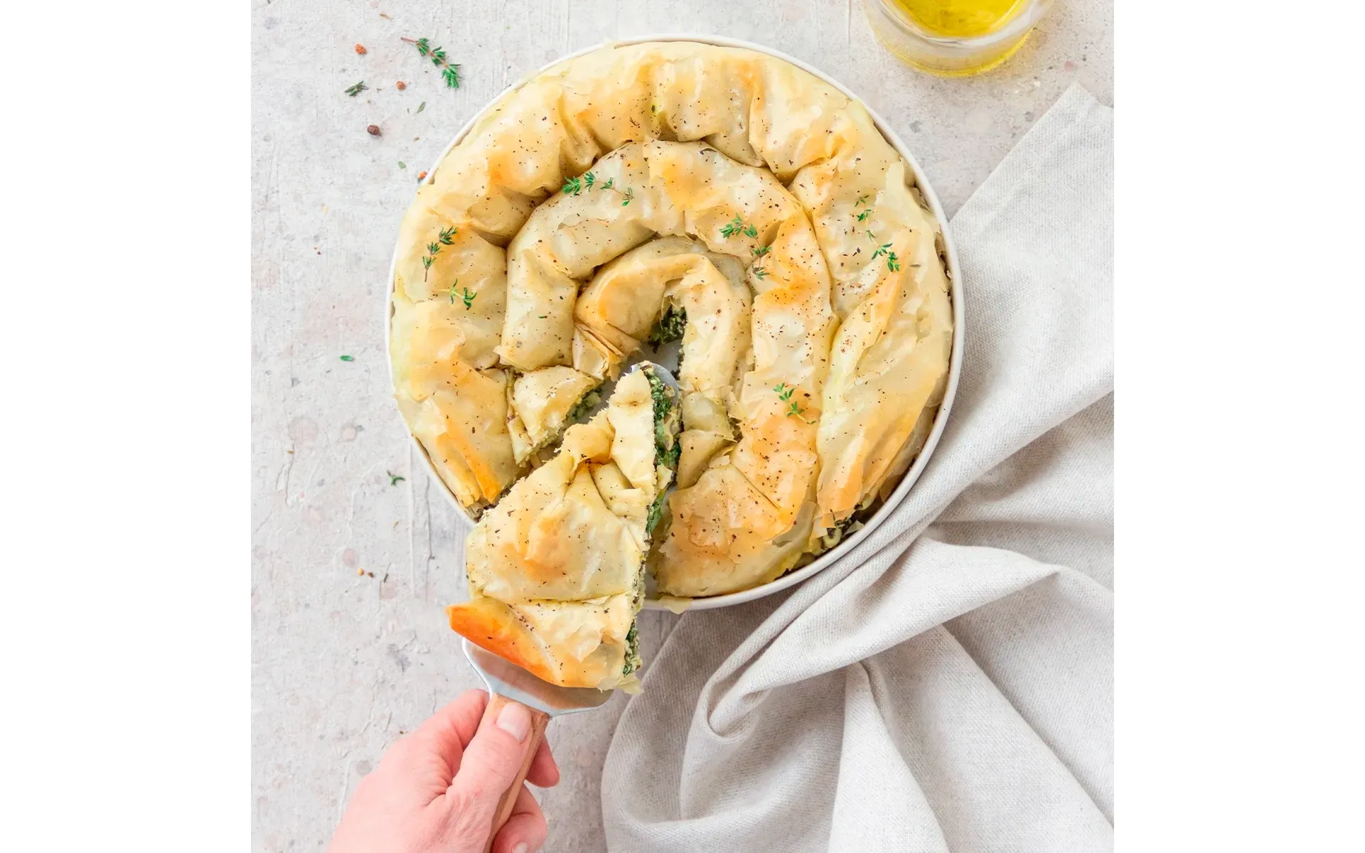 Spanakopita Orogel: torta salata greca con feta e spinaci, servita in una ciotola con cucchiaio.