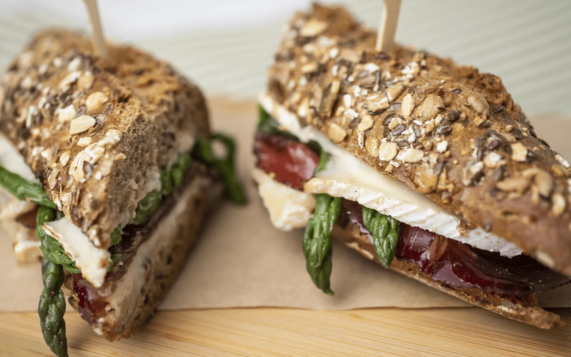 Baguette integrale Orogel con asparagini, brie e bresaola: un panino raffinato su tagliere.