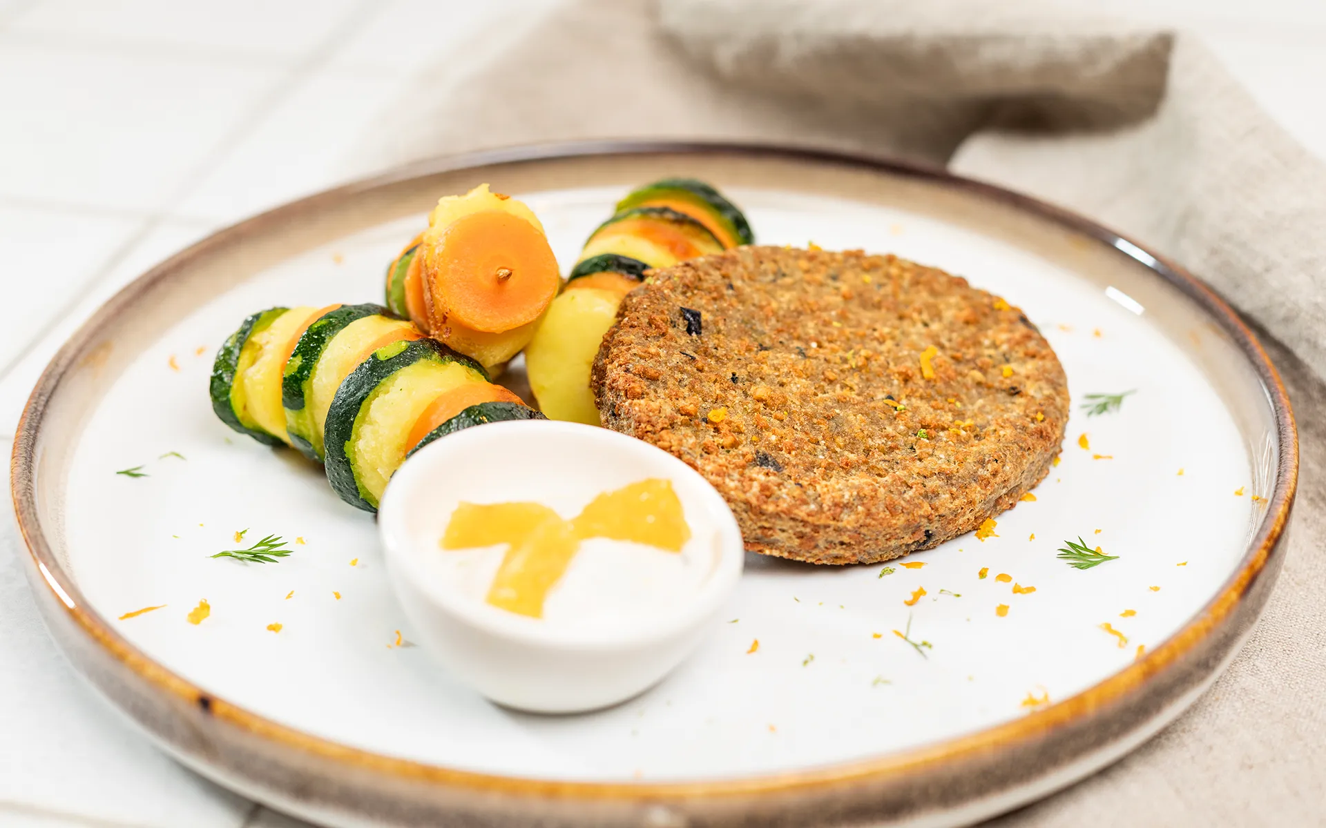 Burger Orogel (di carne o vegetale) servito con un contorno abbondante di verdure fresche.