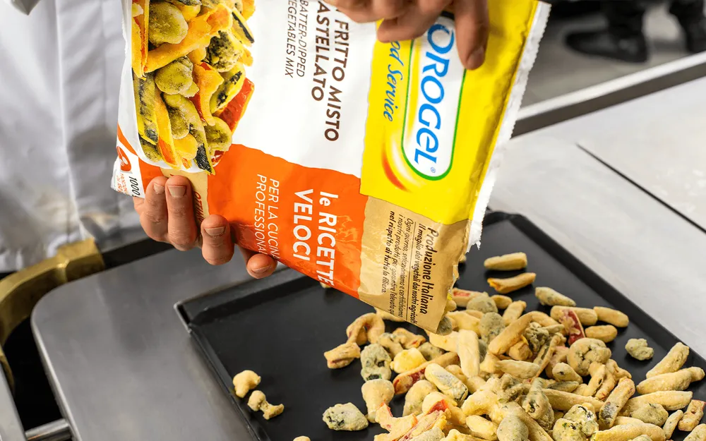 Confezionamento in Box Orogel: una persona sistema un sacchetto di patatine in un vassoio.