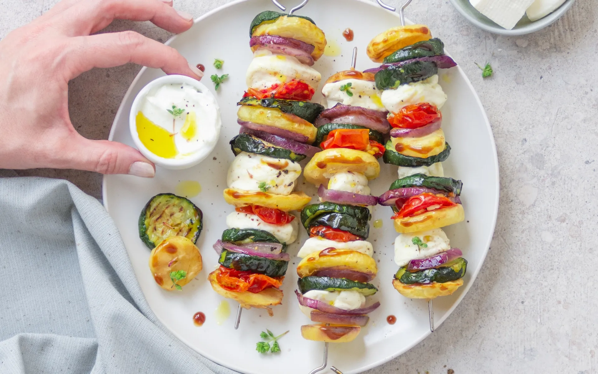 Spiedini di verdure con zucchine, pomodorini, cipolla rossa, patate e primosale serviti su un piatto