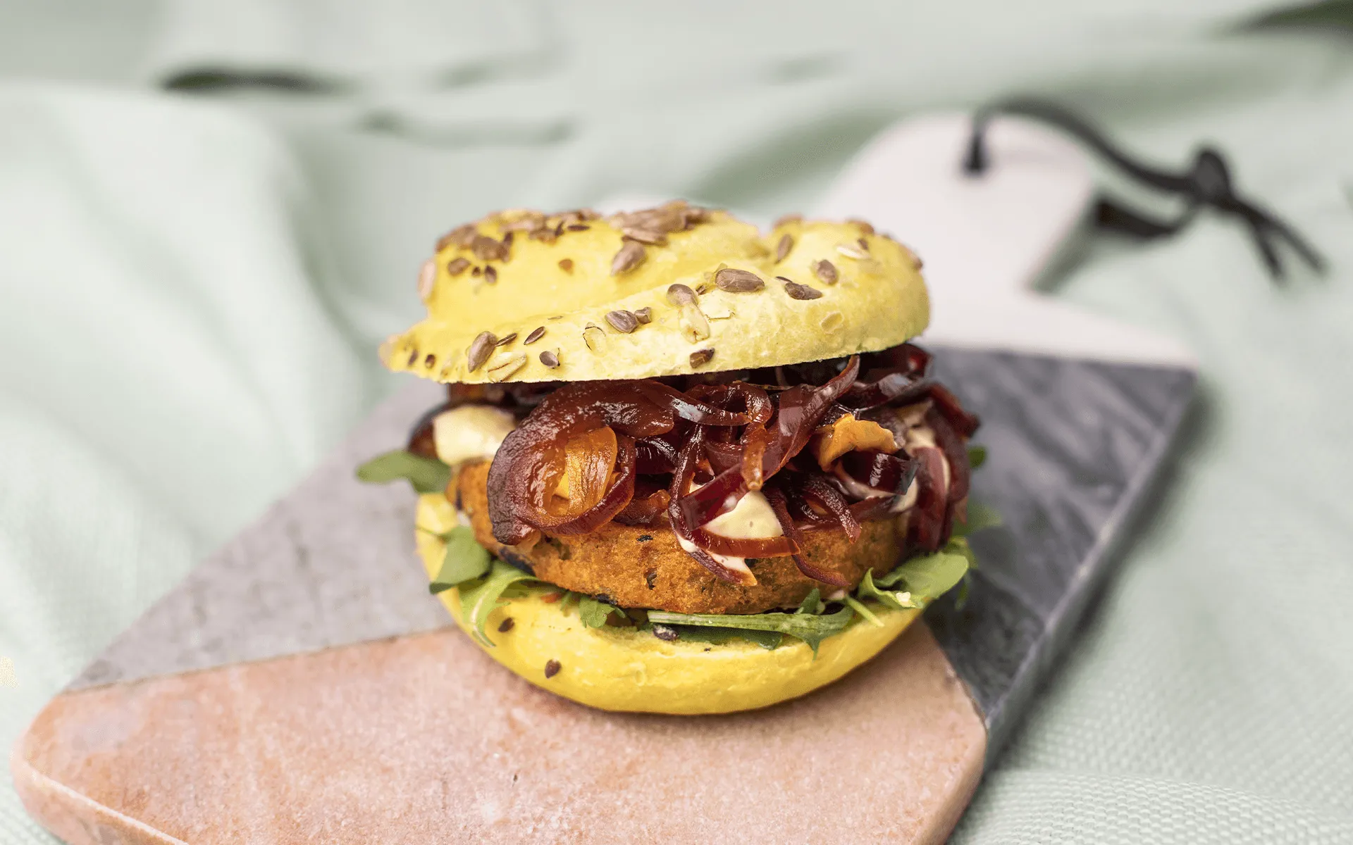 Panino Orogel cereali e curcuma con burger di verdure grigliate, scamorza, salsa tartara e cipolla.