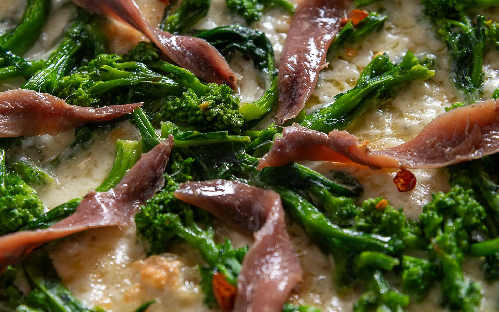 Pizza con mozzarella filante, cime di rapa e acciughe, dal gusto deciso e mediterraneo.