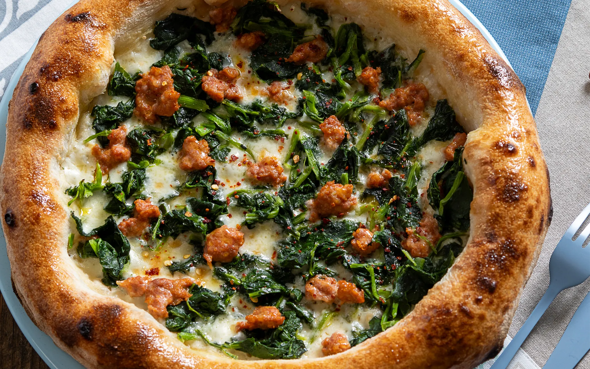 Pizza con mozzarella filante, friarielli e salsiccia piccante, dal gusto intenso e avvolgente.