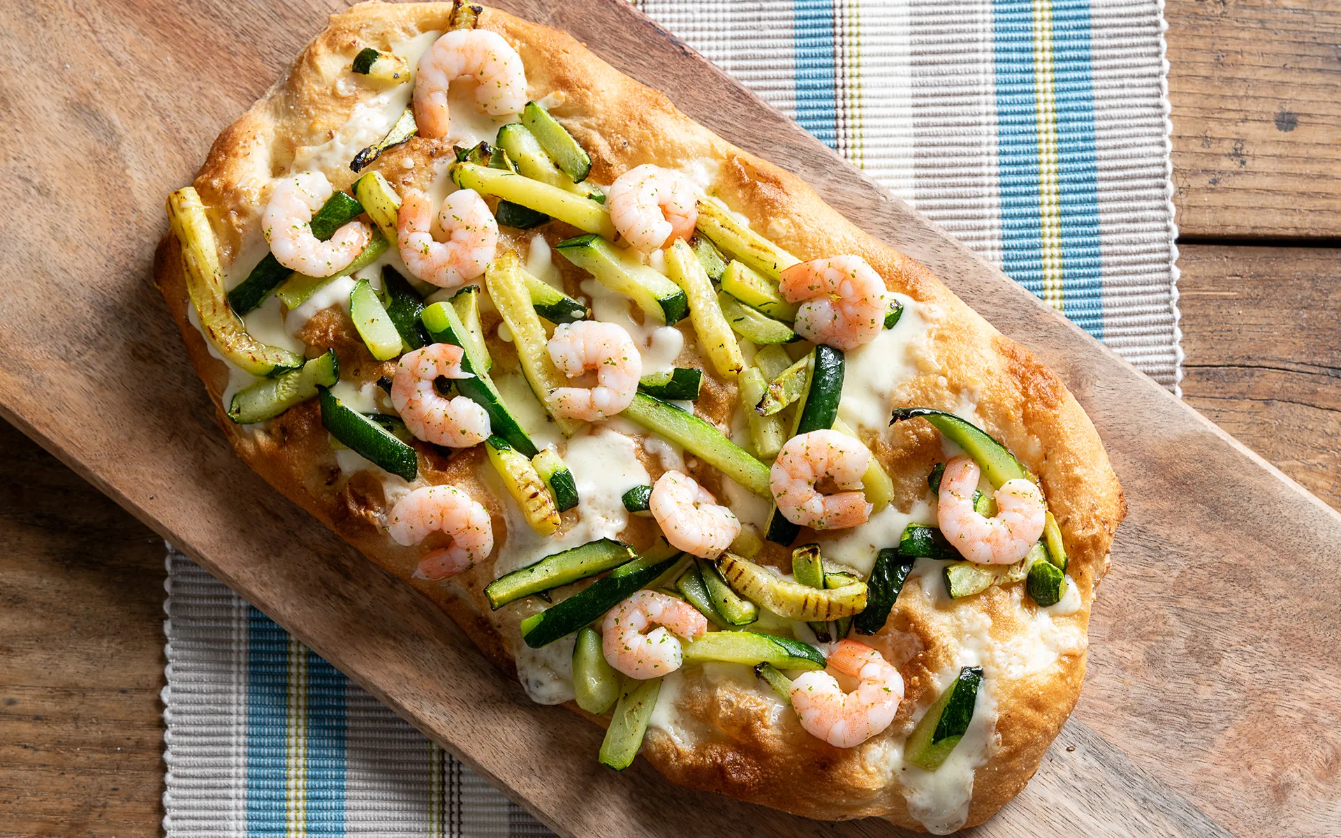 Pizza con mozzarella filante, zucchine grigliate e gamberi, dal gusto delicato e aromatico.