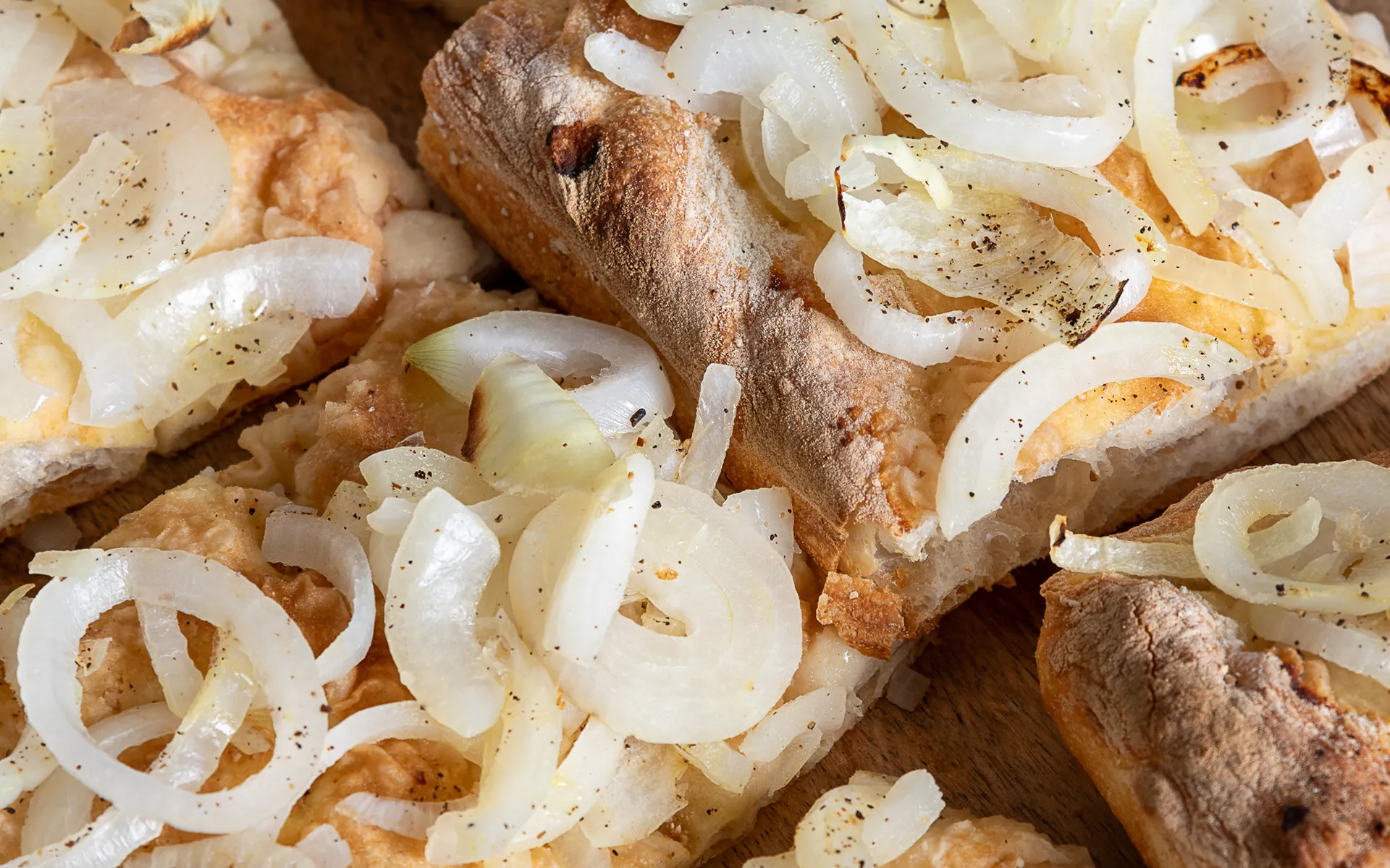 Pizza in teglia con cipolla, dorata in superficie e dalla consistenza soffice e fragrante.