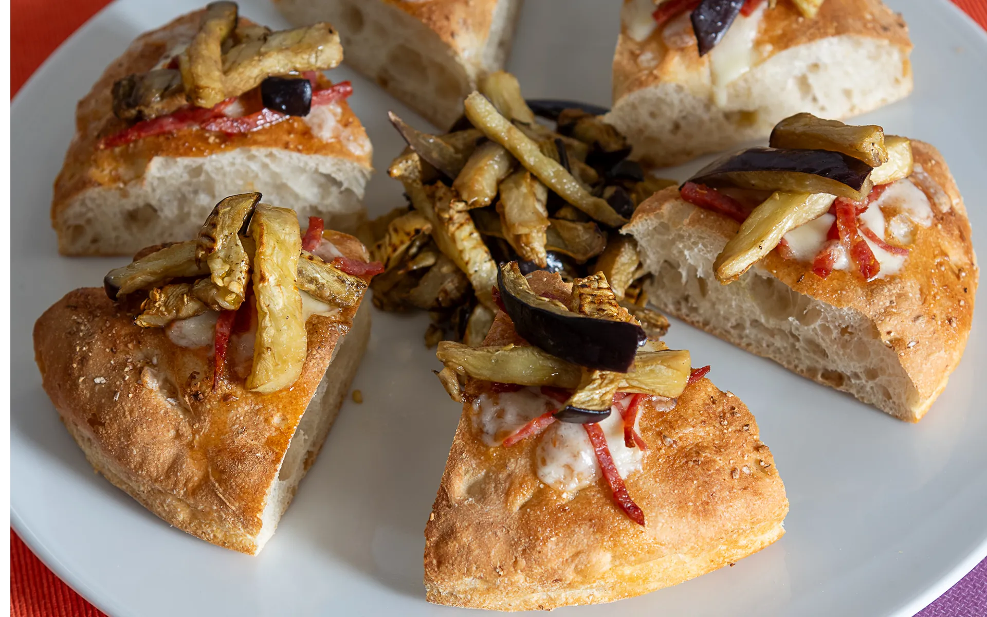 Pizza tonda al tegamino con mozzarella filante, melanzane stick grigliate e pancetta affumicata, dal gusto ricco e deciso.