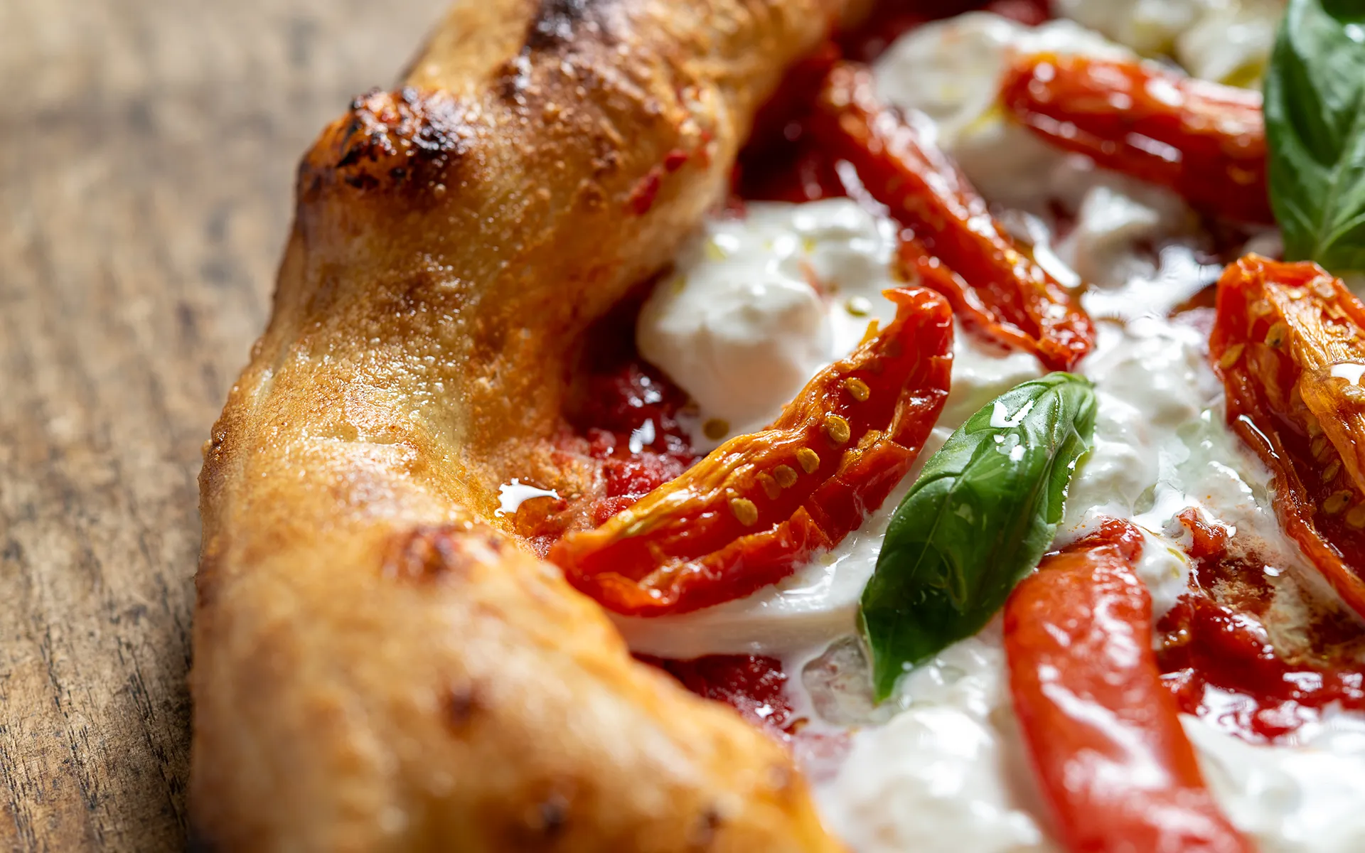 Pizza contemporanea con pomodoro, mozzarella di bufala, pomodori semi dry e basilico, dal profumo fresco e mediterraneo.