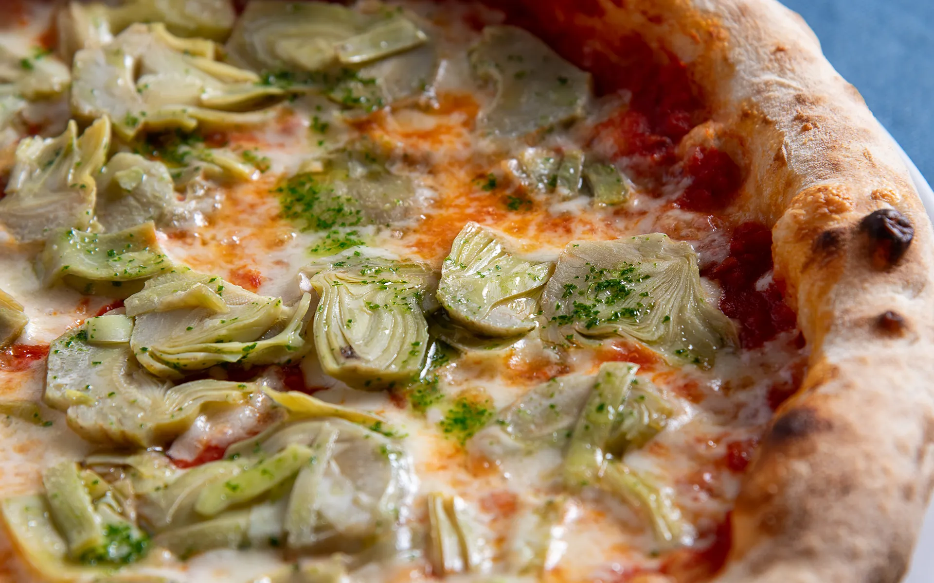 Pizza con pomodoro, mozzarella filante e carciofi, dal gusto equilibrato e mediterraneo.