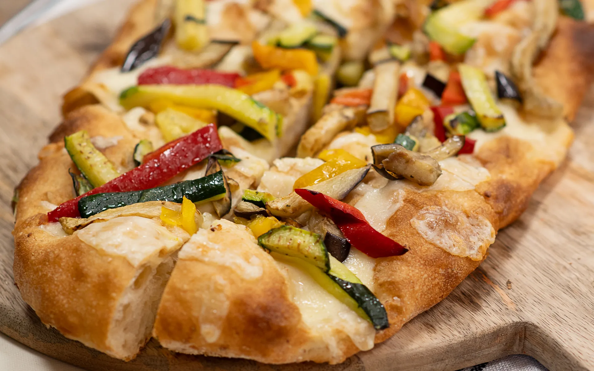 Pizza in teglia con mozzarella filante e verdure grigliate, dal profumo intenso e dall’aspetto invitante.