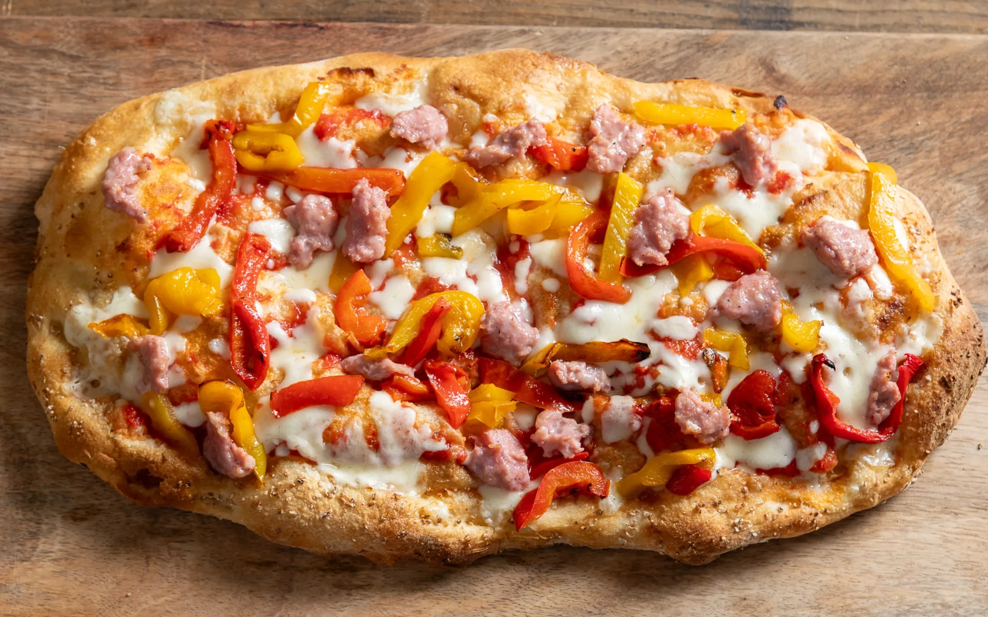 Pizza con mozzarella filante, peperoni arrostiti e salsiccia, appena sfornata e dal gusto intenso