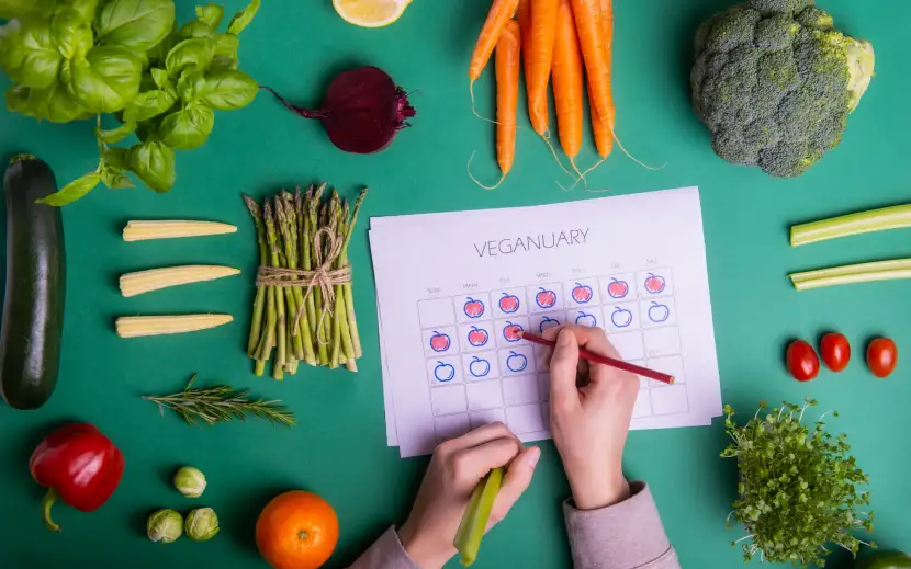 Calendario di gennaio circondato da verdure fresche e di stagione, simbolo del Veganuary e dell’alimentazione vegetale consapevole.