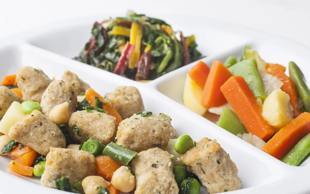 Soluzioni pasto in box Orogel: due piatti bianchi con pollo e verdure, per un pranzo completo.