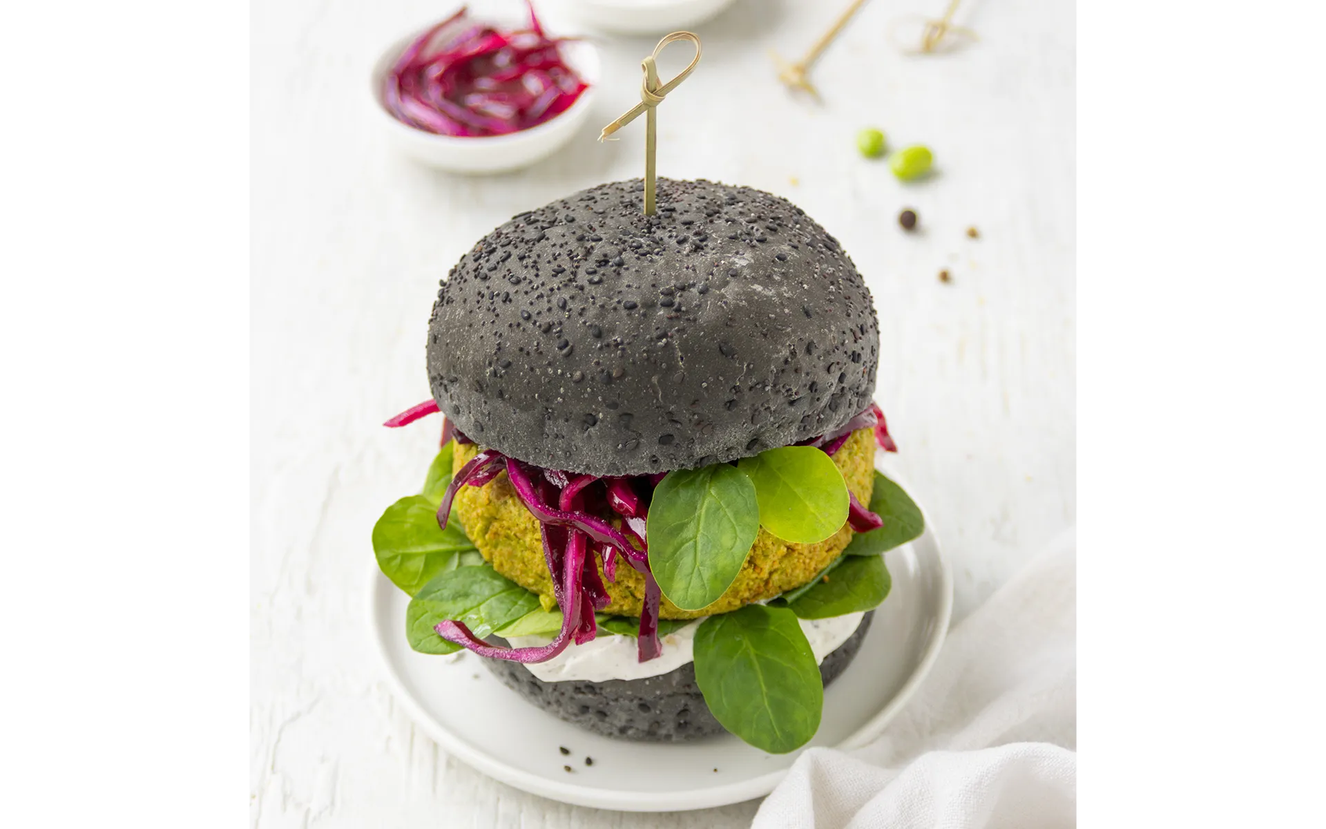 Ricetta burger edamame Orogel: un panino con burger di edamame, sesamo nero e barbabietola.