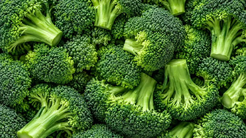 Primo piano di broccoli freschi, con cimette verde intenso e gambi verde chiaro disposti fittamente, fotografati dall’alto.