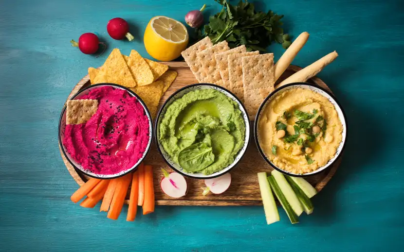 Hummus fatto in casa in tre varianti: hummus di ceci classico, hummus di piselli e hummus di barbabietola, serviti con crudité di verdure, cracker e grissini.