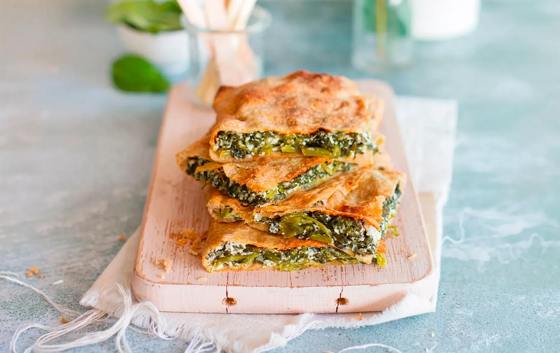 Torta salata a strati con verdure e formaggio, tagliata e servita su tagliere.
