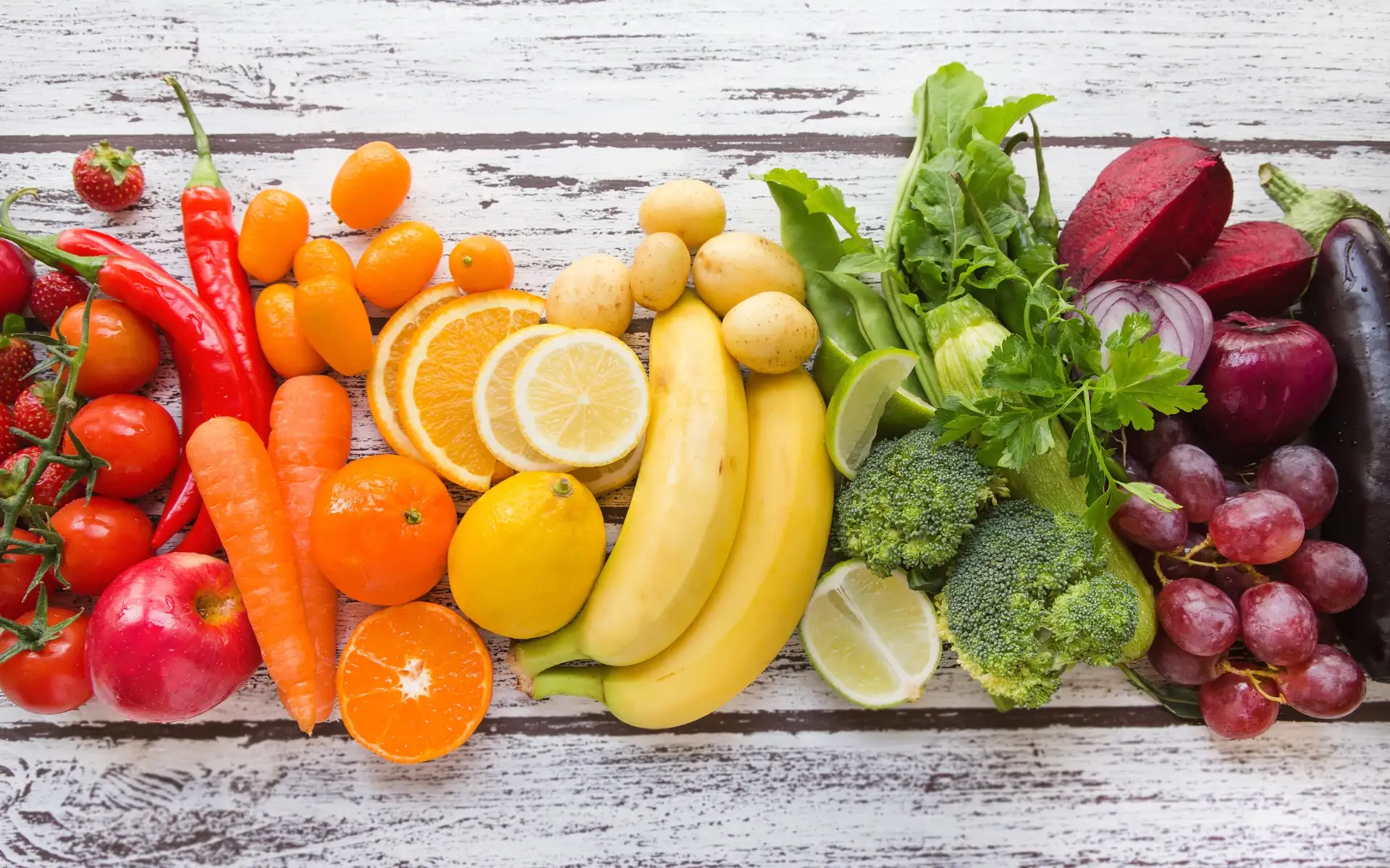 Frutta e verdura disposte in ordine cromatico, con colori che vanno dal verde al rosso, a rappresentare la varietà dei prodotti di stagione.